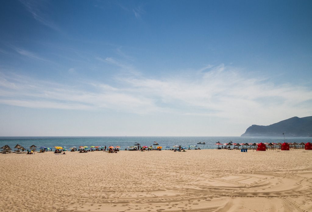 Praia de Figueirinha est appréciée pour son accessibilité et son cadre, magnifié par la montagne d’Arràbida qui se dessine en arrière-plan.